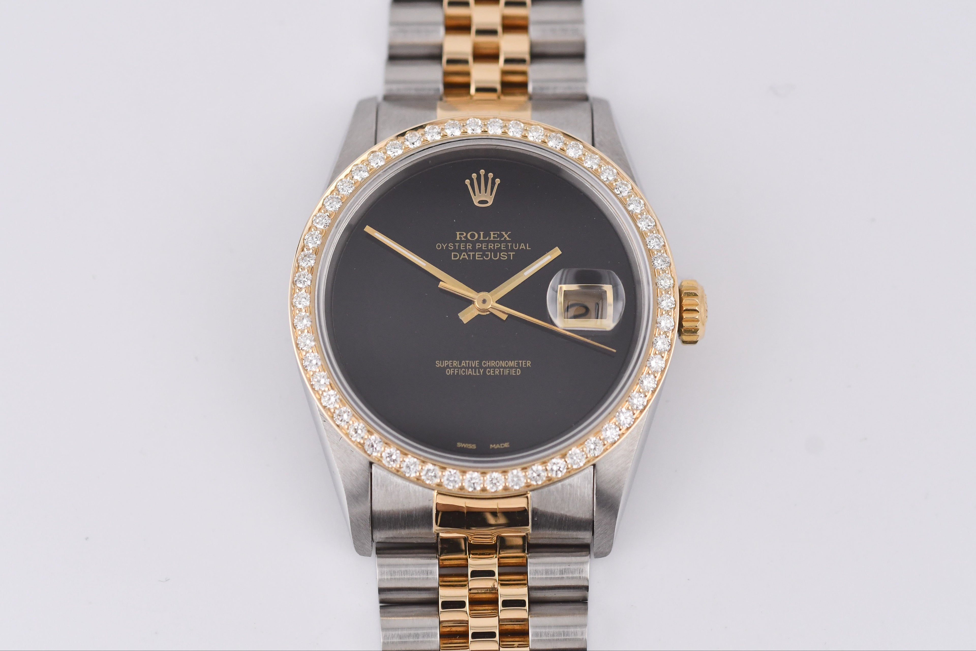 Luxury watch with a dark face and gold and silver band on a light gray background