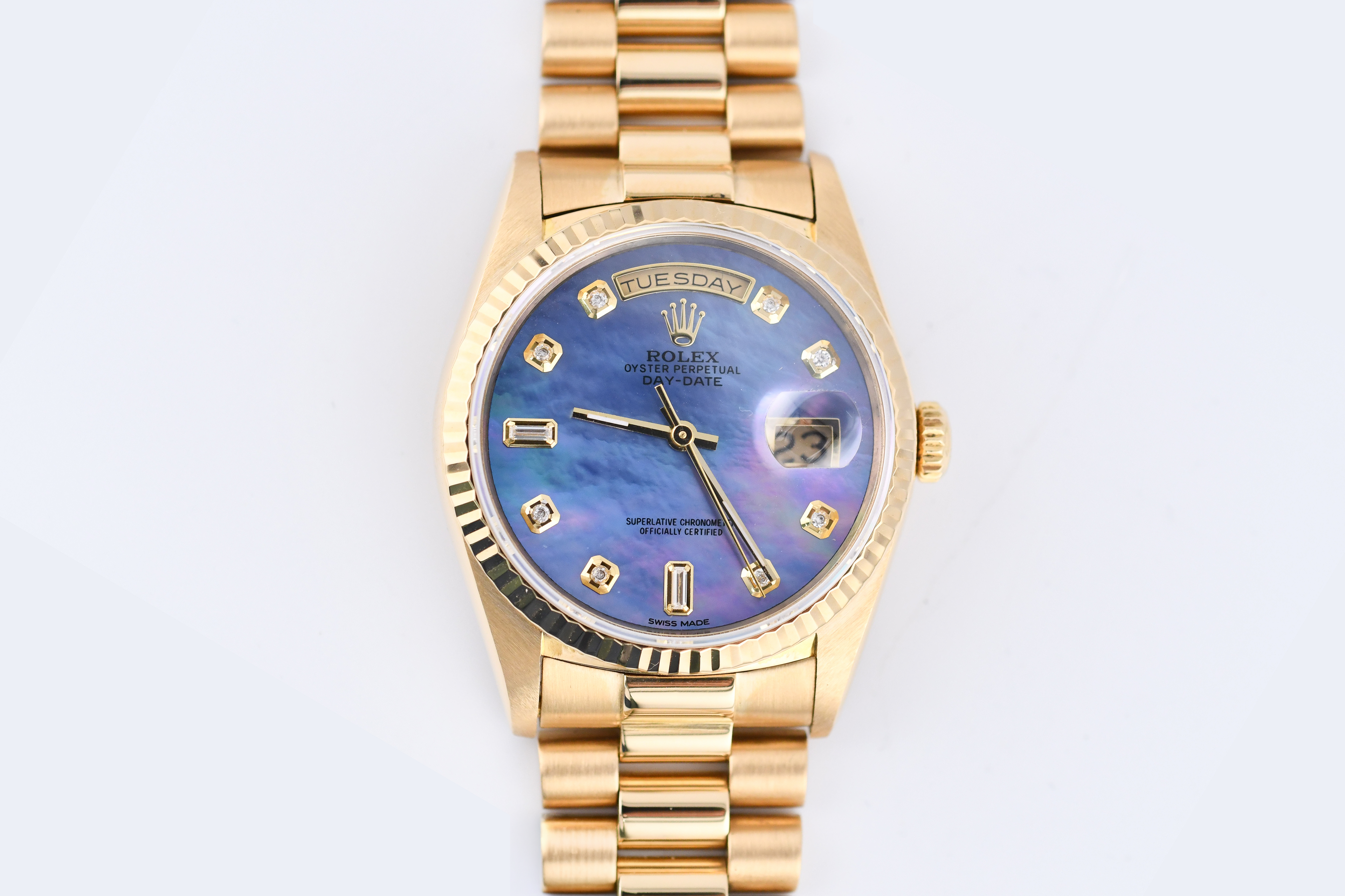 Gold wristwatch with a blue face on a white background