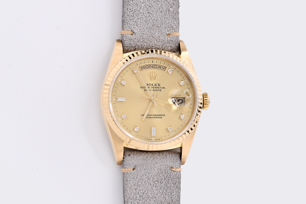 Gold watch with a gray strap on a light gray background