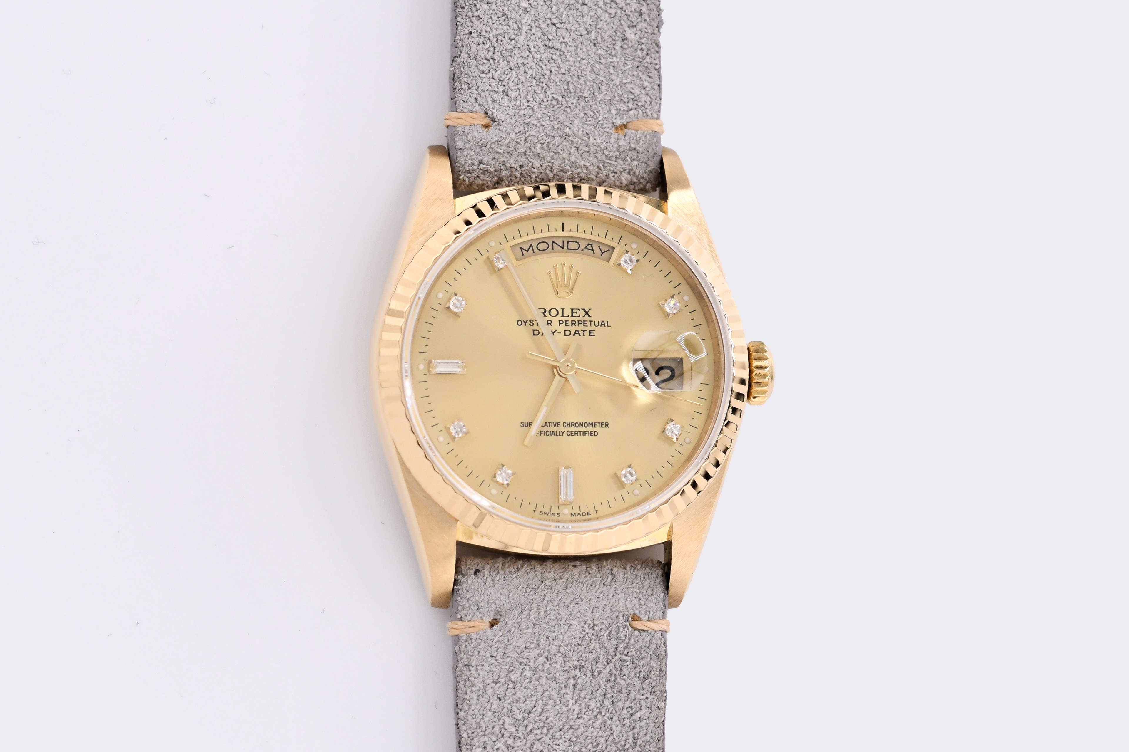 Gold watch with a gray strap on a light gray background