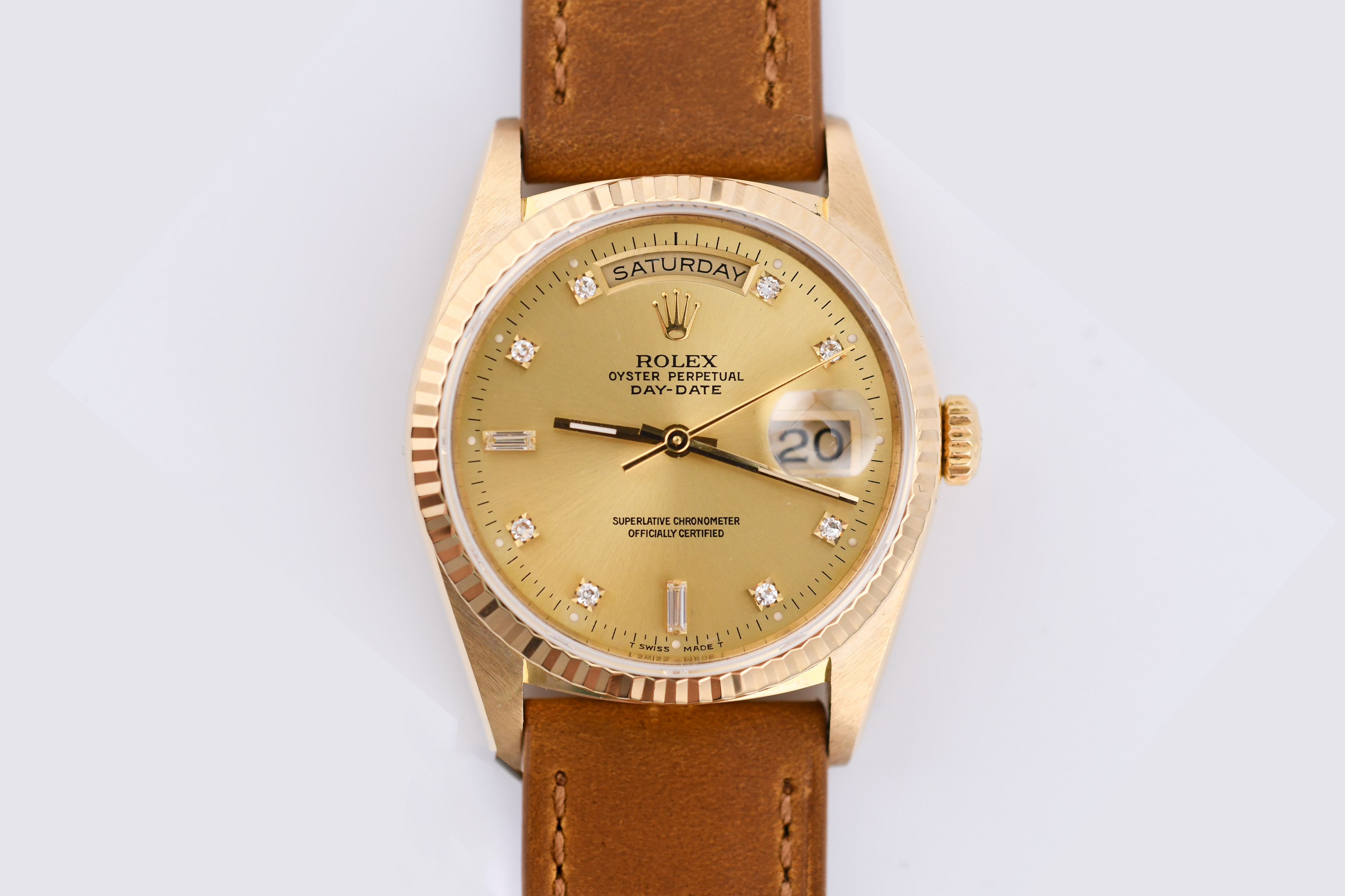 Gold watch with a brown leather strap on a light gray background