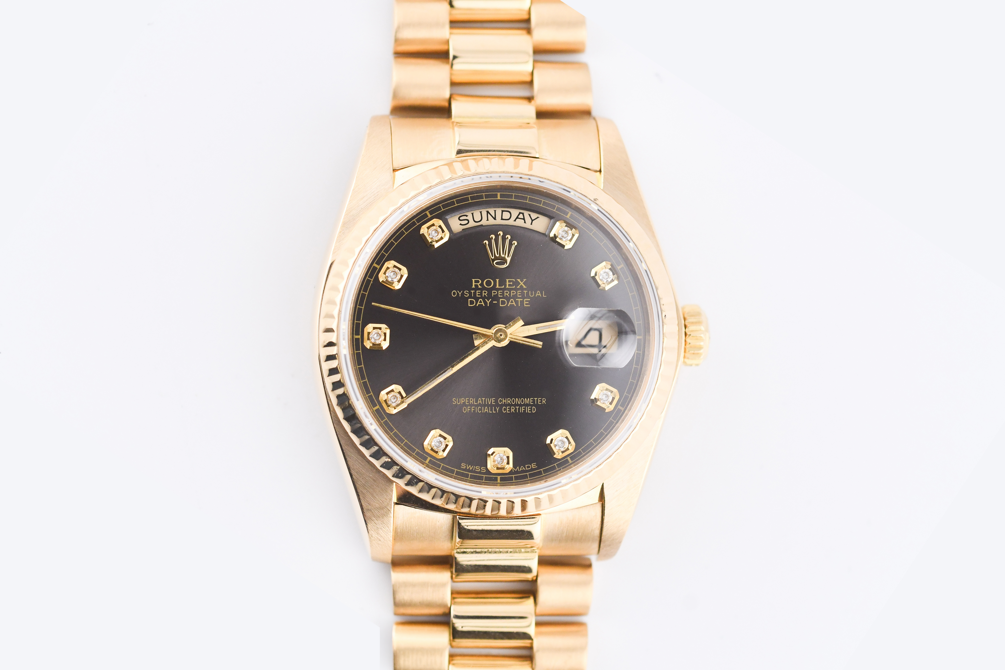 Gold Rolex watch with a black face on a white background