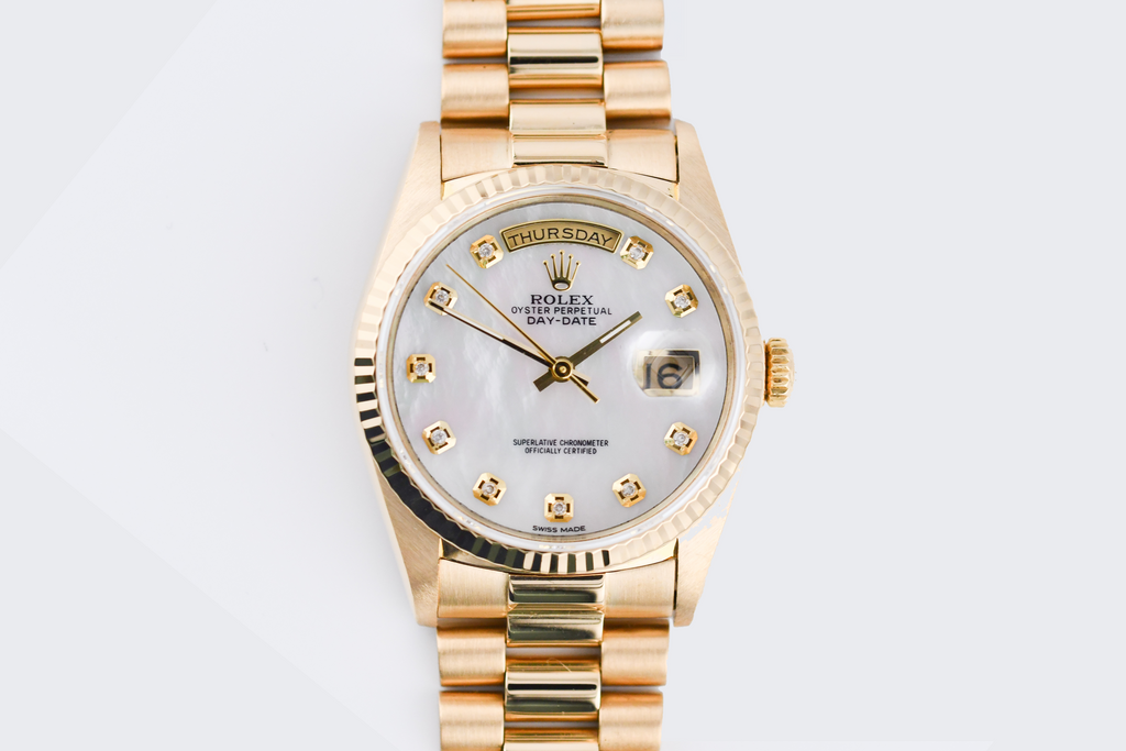Gold wristwatch with a silver face on a light gray background