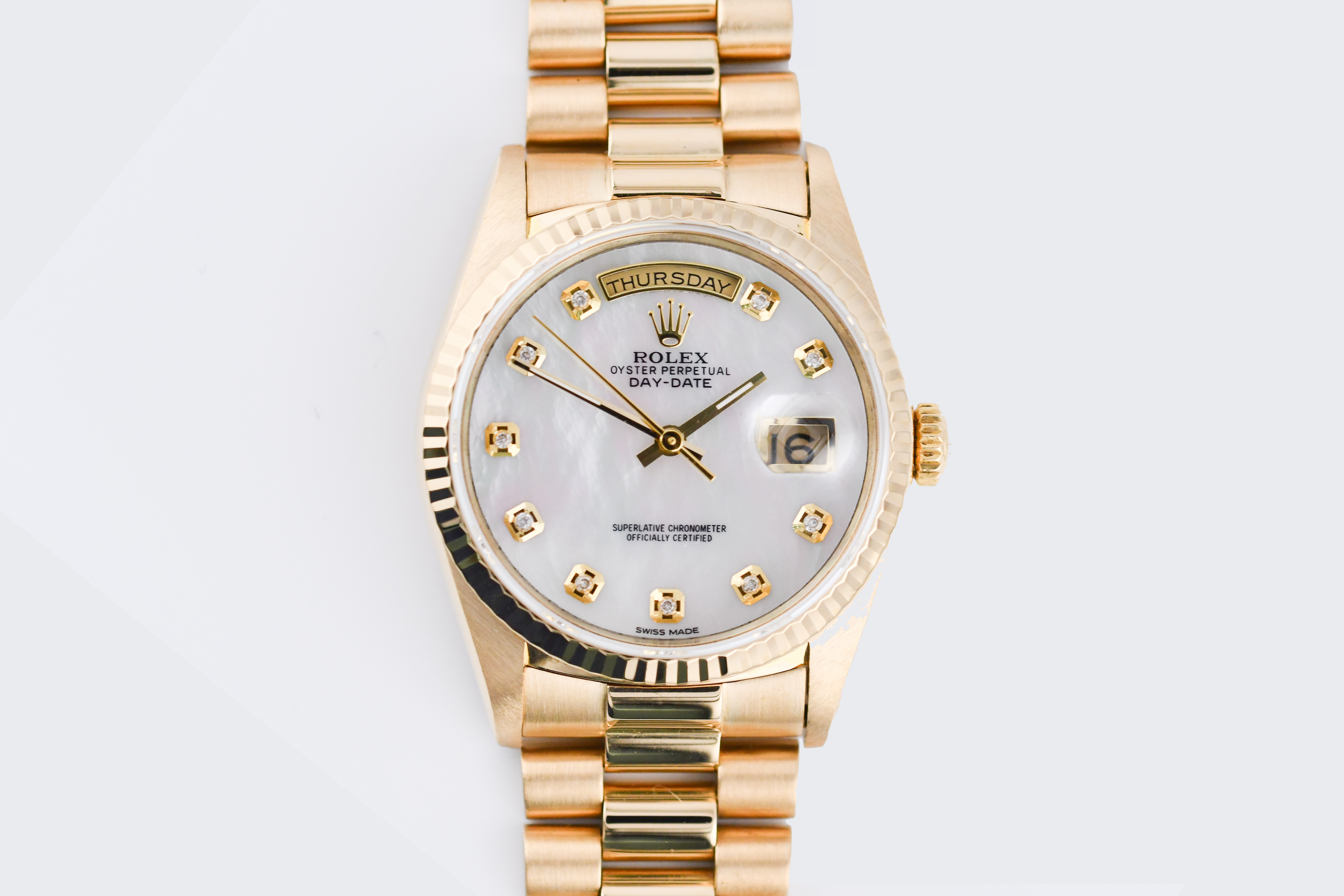 Gold wristwatch with a silver face on a light gray background