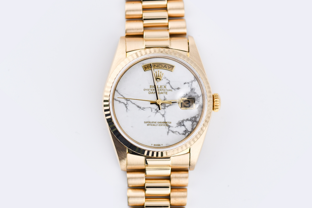 Gold wristwatch with a marble-patterned face on a white background