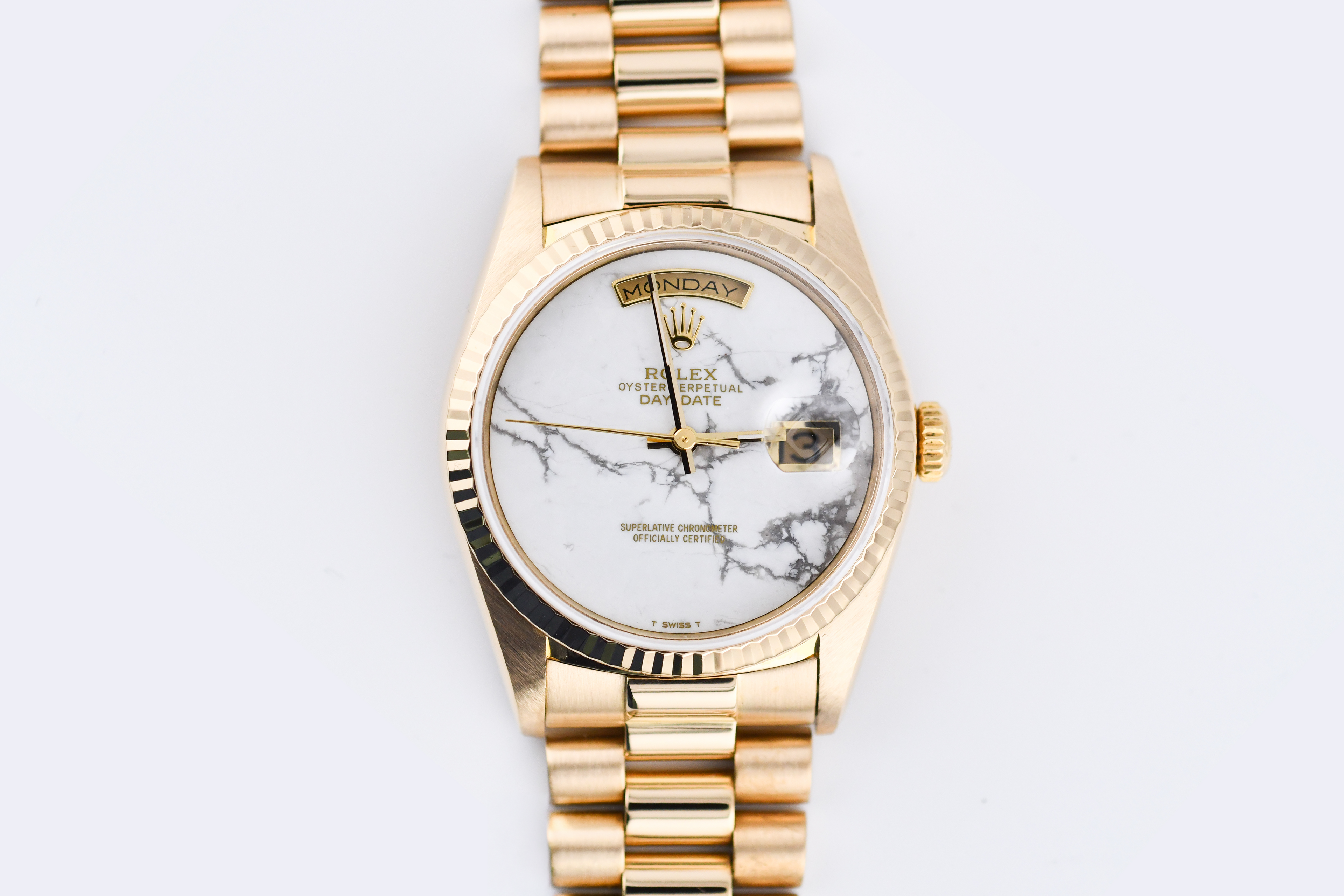Gold wristwatch with a marble-patterned face on a white background