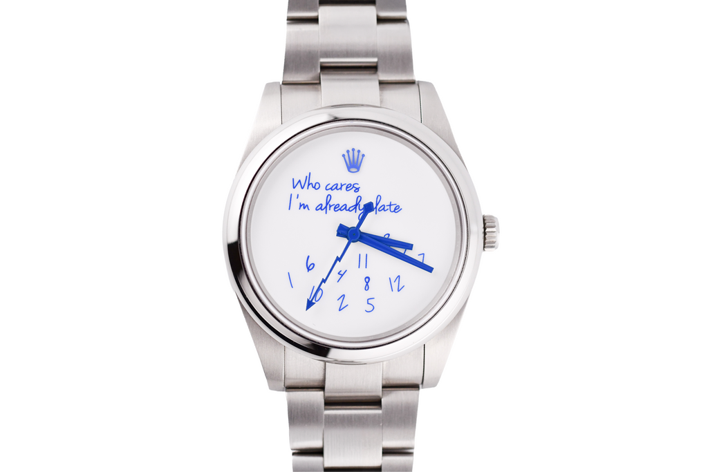 Silver watch with a white face displaying 'Who cares I'm already late' text.