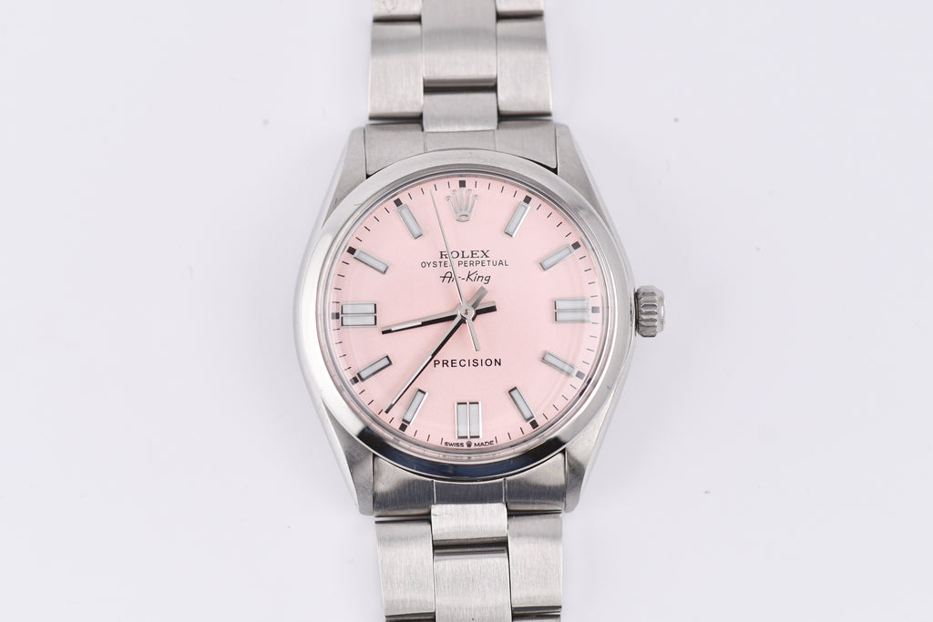 Silver watch with a pink face on a white background