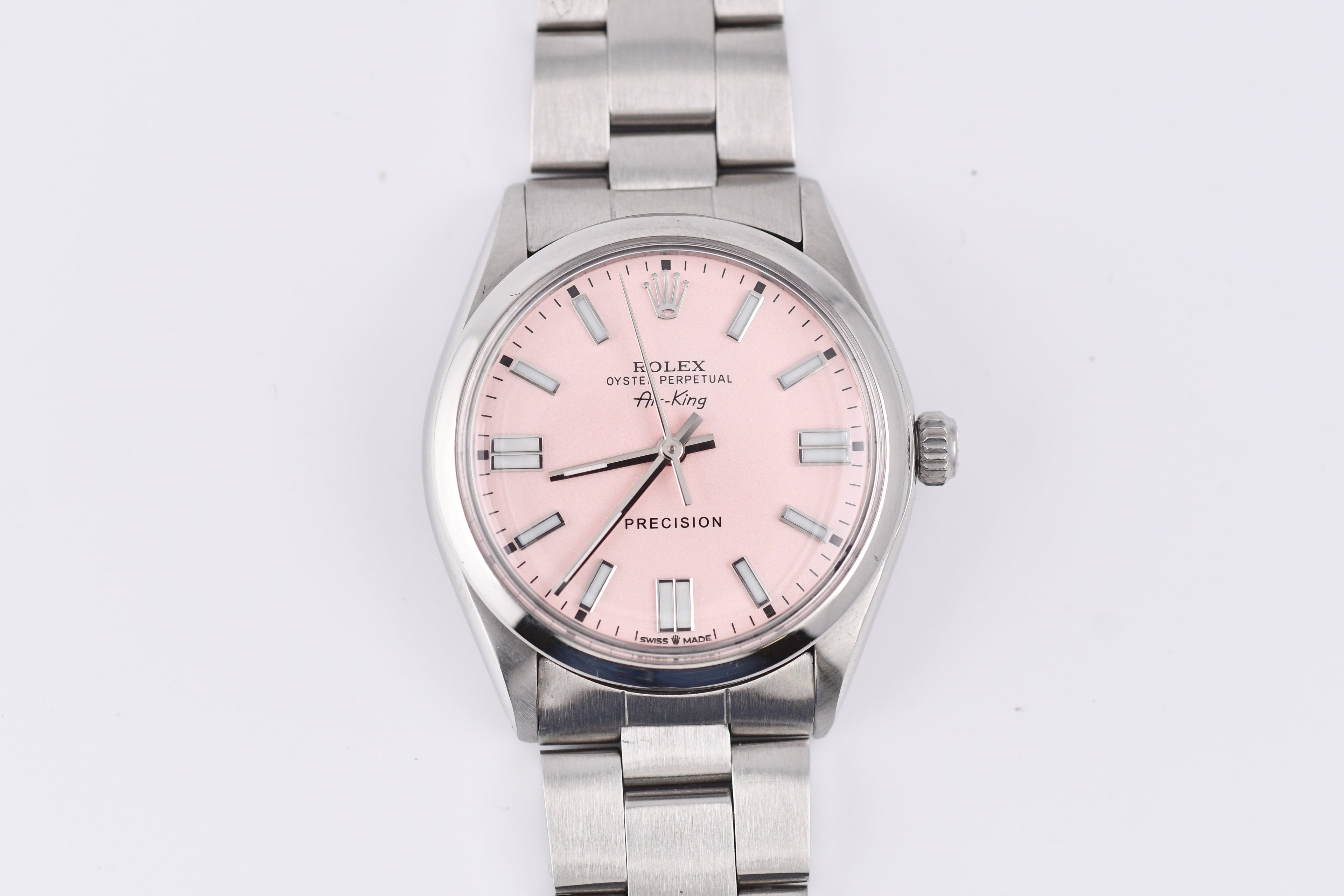Silver watch with a pink face on a white background