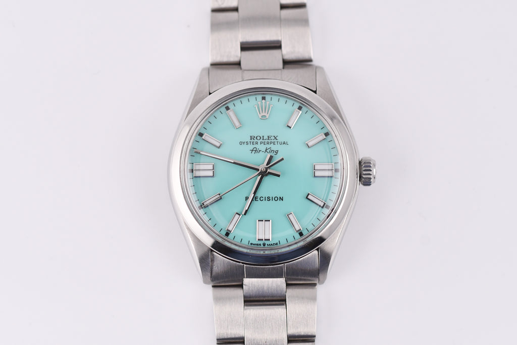Silver Rolex watch with a turquoise dial on a white background