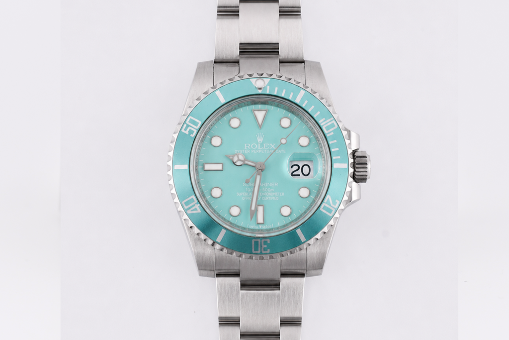 Silver watch with turquoise bezel and face on a white background