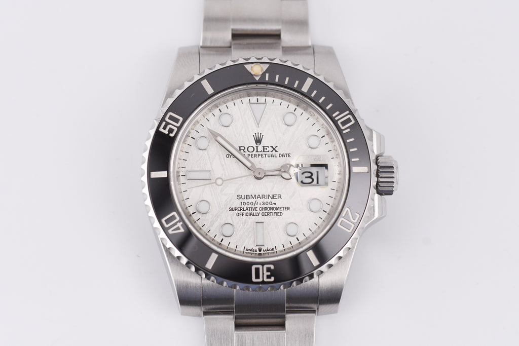 Silver Rolex watch with a white face on a light gray background
