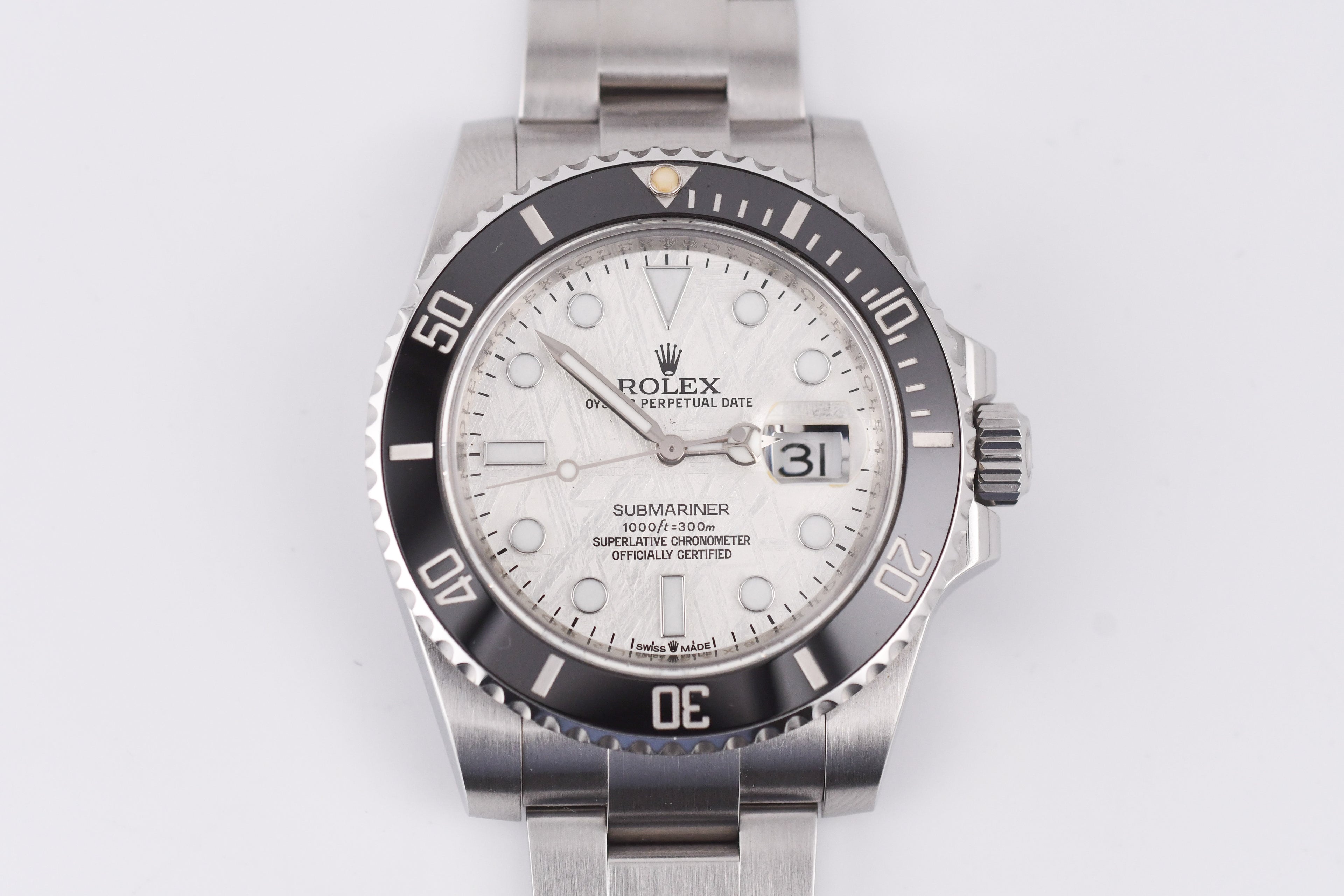 Silver Rolex watch with a white face on a light gray background